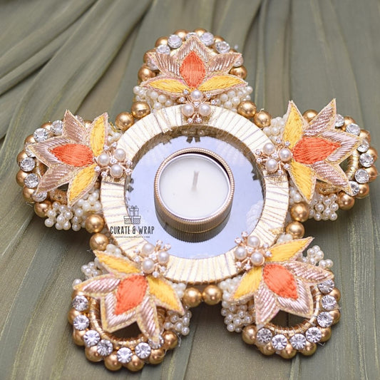 Decorative candle holder with floral designs and pearls on a green fabric background