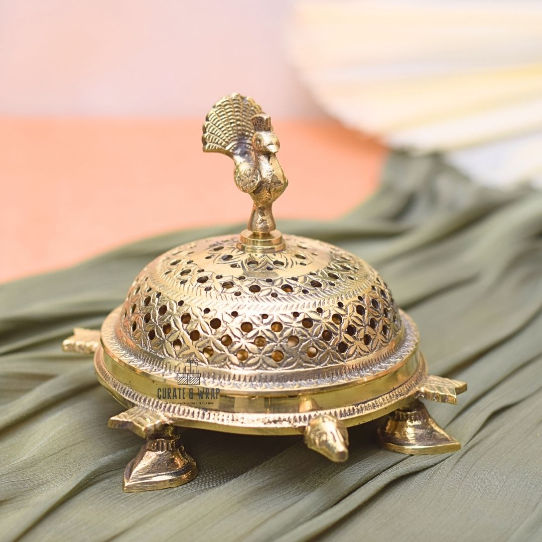 Decorative brass turtle with intricate design on a green fabric background