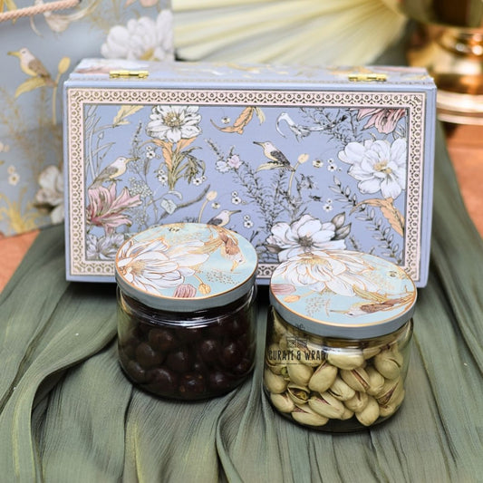 Two jars of nuts with decorative lids on a floral-patterned box.
