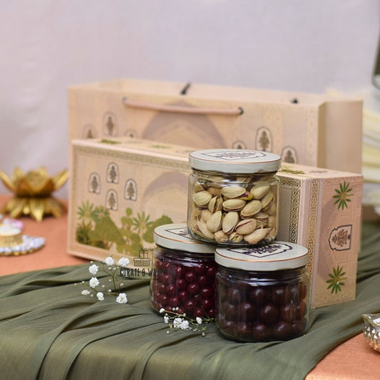 Three glass jars with lids containing nuts on a green fabric with decorative elements.