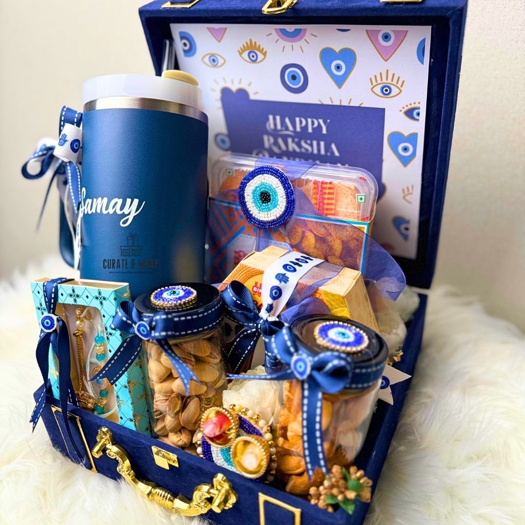 Gift basket with a blue tumbler, snacks, and decorative items in a blue box.