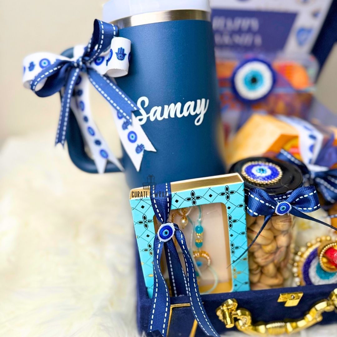 Blue tumbler with 'Samay' text, decorative items, and a box on a neutral background