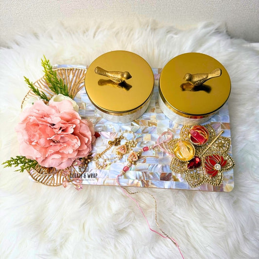 Two gold-lidded jars with decorative elements on a textured white surface