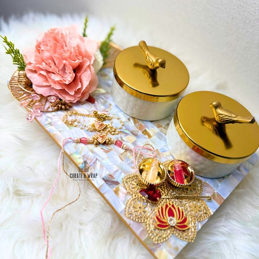 Decorative items including gold jewelry, pink flowers, and ceramic containers on a textured surface.
