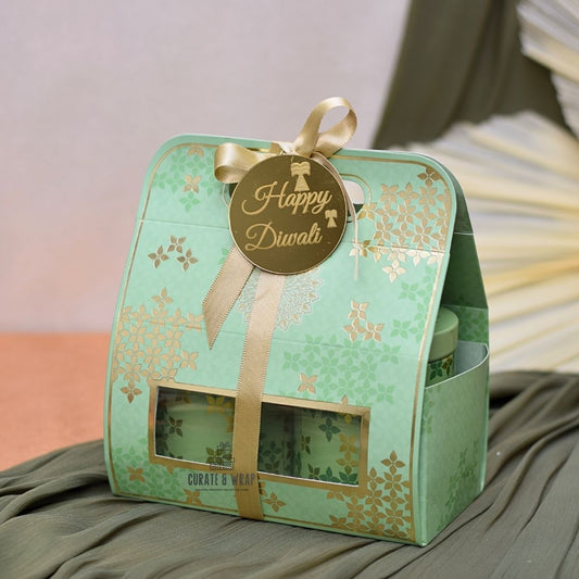 Green gift box with 'Happy Diwali' tag and gold ribbon on a soft surface