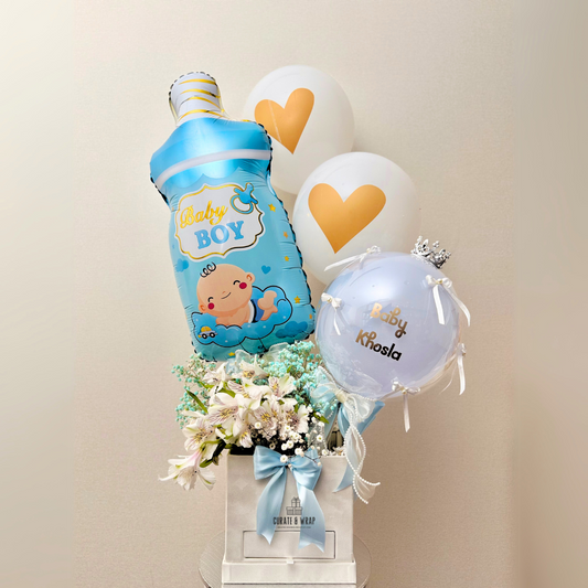 Luxury baby boy birth announcement hamper with personalized balloons, fresh flowers, and chocolates in a white gift box.