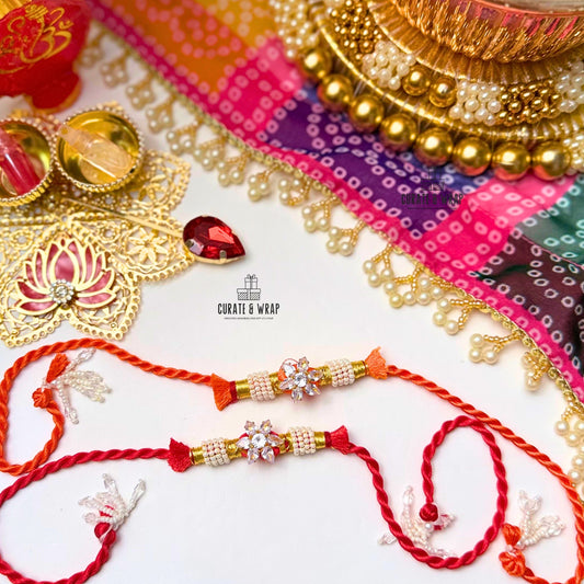 Two red and gold rakhi with decorative elements on a colorful background