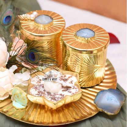 Gold decorative items with peacock feathers and flowers on a white surface