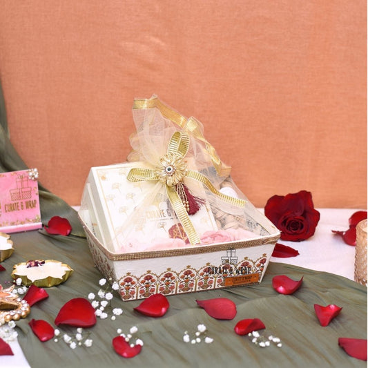 Decorative gift box with a bow on a table with rose petals
