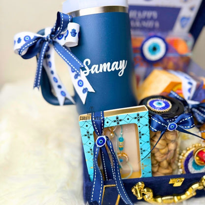 Blue tumbler with 'Samay' text, decorative items, and a box on a neutral background