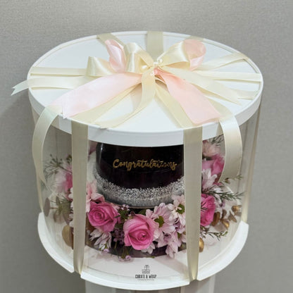 Luxury gift hamper with half kg cake and fresh pink flowers in a round box by Curate and Wrap, ideal for all occasions.