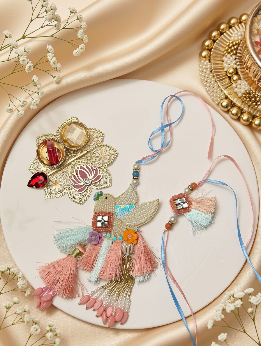A decorative Rakhi with pink and blue threads, embellished with a bird motif, colorful beads, and pink tassels, displayed alongside a matching ornate brooch on a beige satin background.