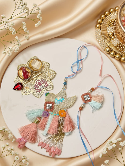 A decorative Rakhi with pink and blue threads, embellished with a bird motif, colorful beads, and pink tassels, displayed alongside a matching ornate brooch on a beige satin background.
