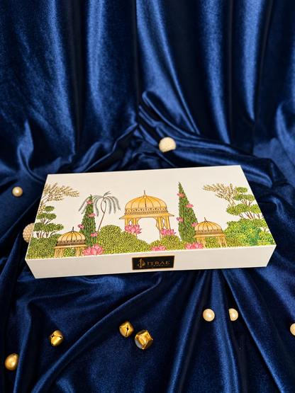 Itrae Home Dhanya Candle Box featuring two 5.5-inch gold metal Urli scented candles, candle snuffer and matchbox in an ivory satin-lined gift box