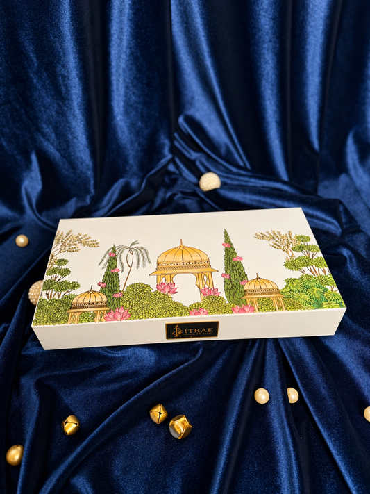 Itrae Home Dhanya Candle Box featuring two 5.5-inch gold metal Urli scented candles, candle snuffer and matchbox in an ivory satin-lined gift box