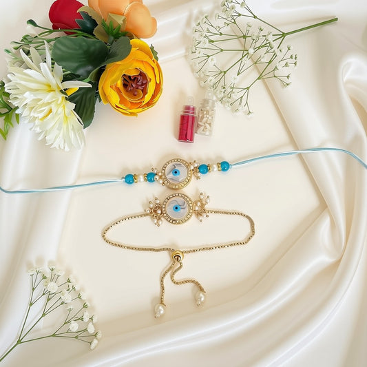 Two delicate jewelry pieces arranged on a cream satin fabric with flowers as props: a thin light blue string bracelet with turquoise and evil eye beads, and a gold-tone chain bracelet with matching evil eye and pearl details. A small pink bottle of glitter sits above them.
