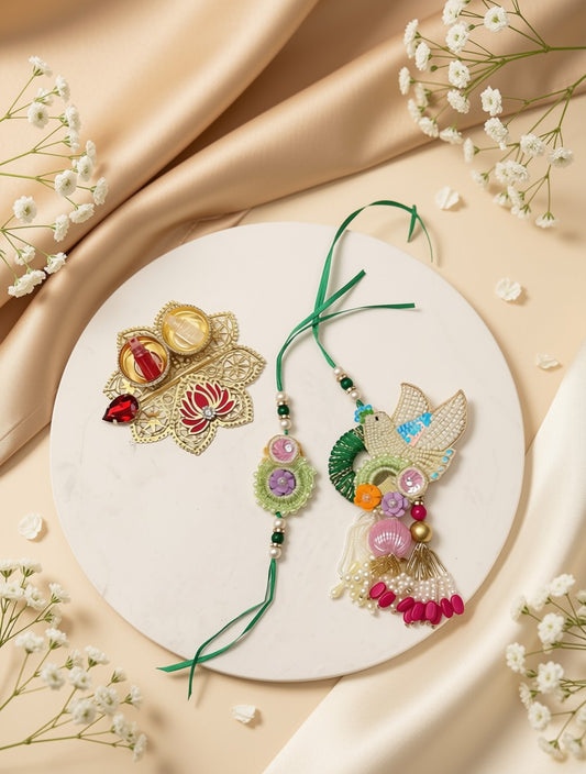 Two decorative Rakhi thread ornaments displayed on a round white plate, surrounded by beige satin fabric and small white flowers. One Rakhi is gold-toned with red and yellow embellishments, and the other is multicolored with green, pink, purple, and blue details.