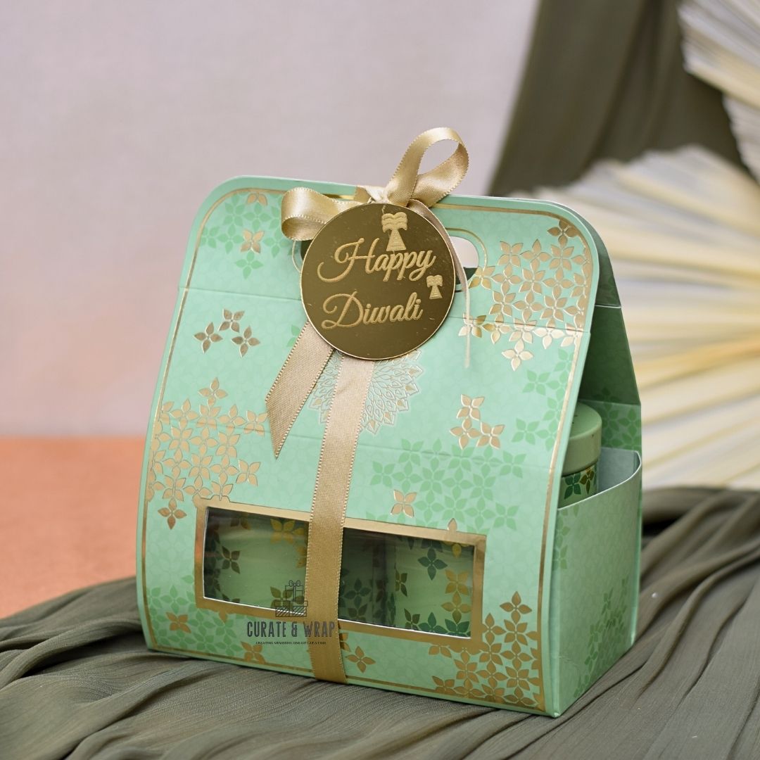 Green gift box with 'Happy Diwali' tag and gold ribbon on a soft surface